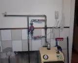 Montaż pompy CO w układzie otwartym. Widoczna instalacja hydrauliczna, czerwona pompa, zawory i fragment kotła.