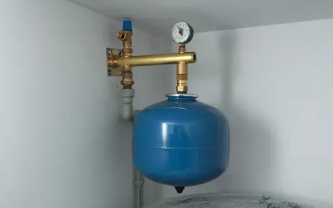 Niebieski zbiornik wyrównawczy co z manometrem, podłączony do instalacji grzewczej.