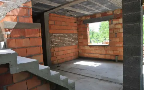 Budynek gospodarczy w trakcie samowolnego przekształcenia na mieszkalny. Widać schody, ściany z pustaków ceramicznych i betonowy strop.