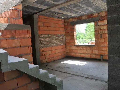 Budynek gospodarczy w trakcie samowolnego przekształcenia na mieszkalny. Widać schody, ściany z pustaków ceramicznych i betonowy strop.