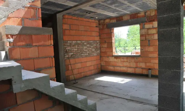 Budynek gospodarczy w trakcie samowolnego przekształcenia na mieszkalny. Widać schody, ściany z pustaków ceramicznych i betonowy strop.