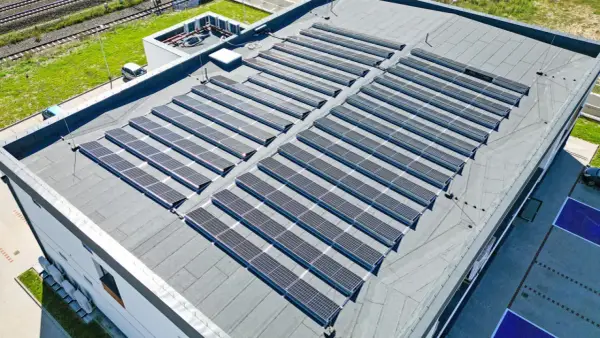 Nowoczesny dom z płaskim dachem pokryty panelami słonecznymi, które czerpią energię z promieni słonecznych.